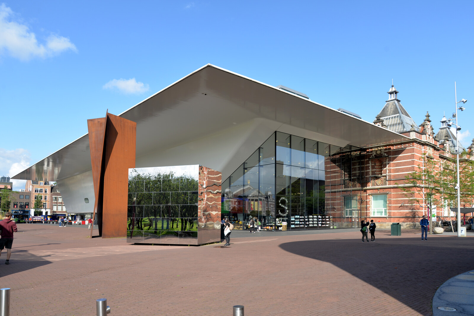 The white shell of the Stedelijk Museum reflecting the sky, with the adjoining brick building.