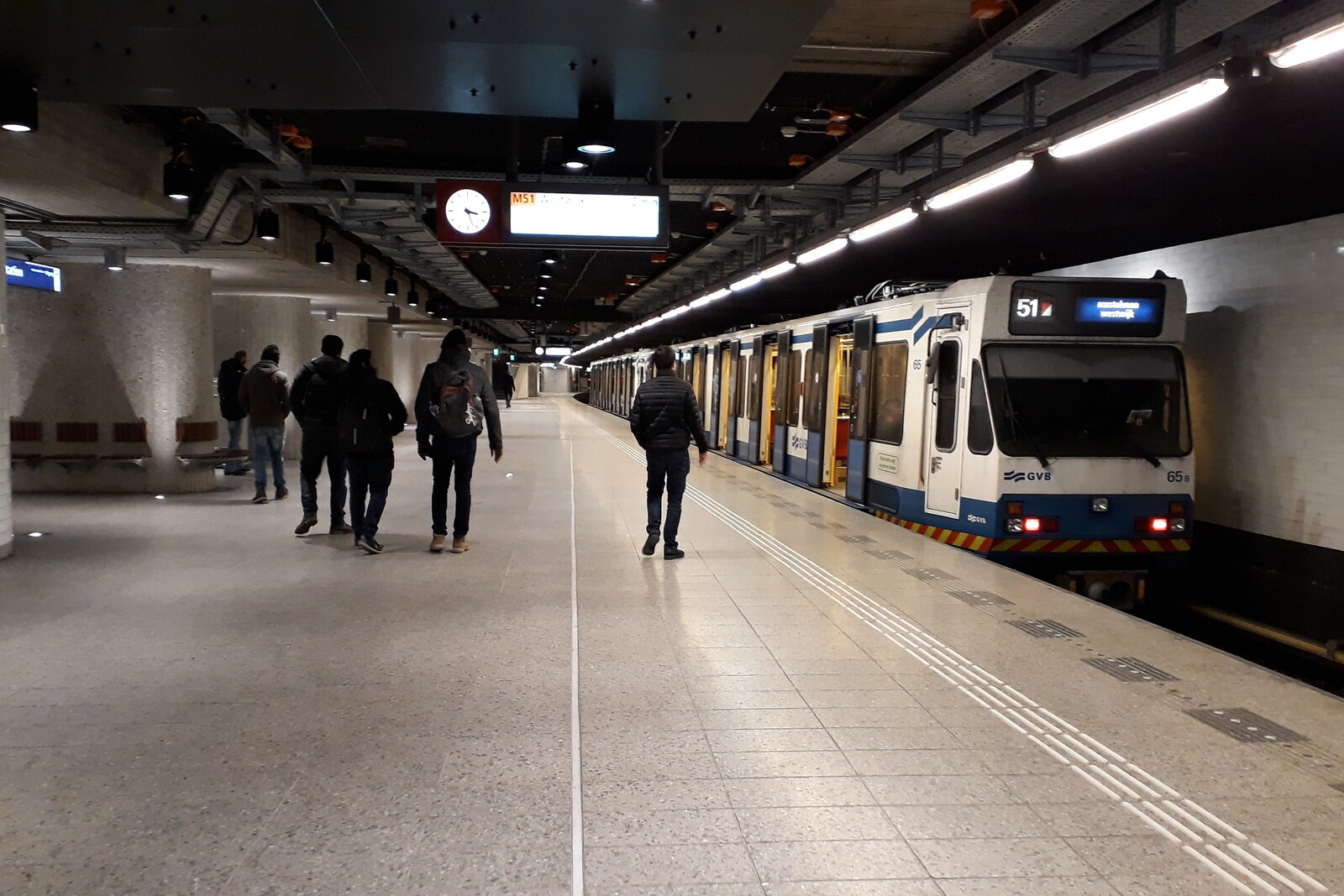 The red-brick facade of Amsterdam Centraal with two towers and the glass roof of the platforms.