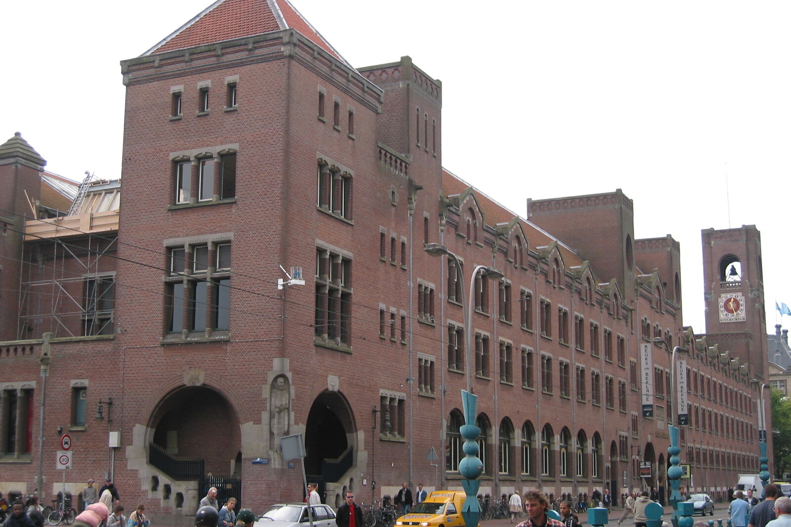 A red-brick building with a clock tower and arches on Damrak.