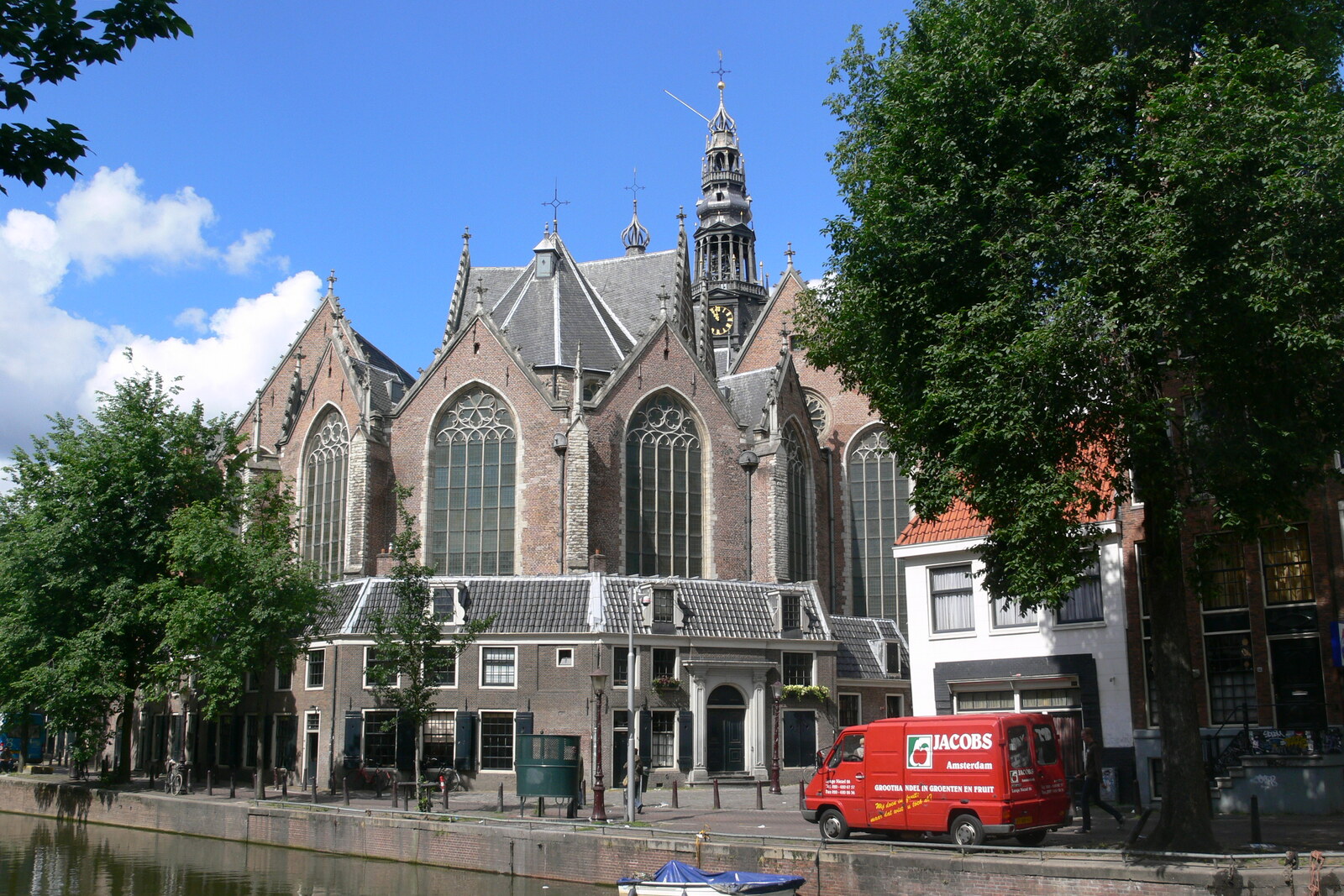 A brick church with a high tower and a four-sided spire against a blue sky.
