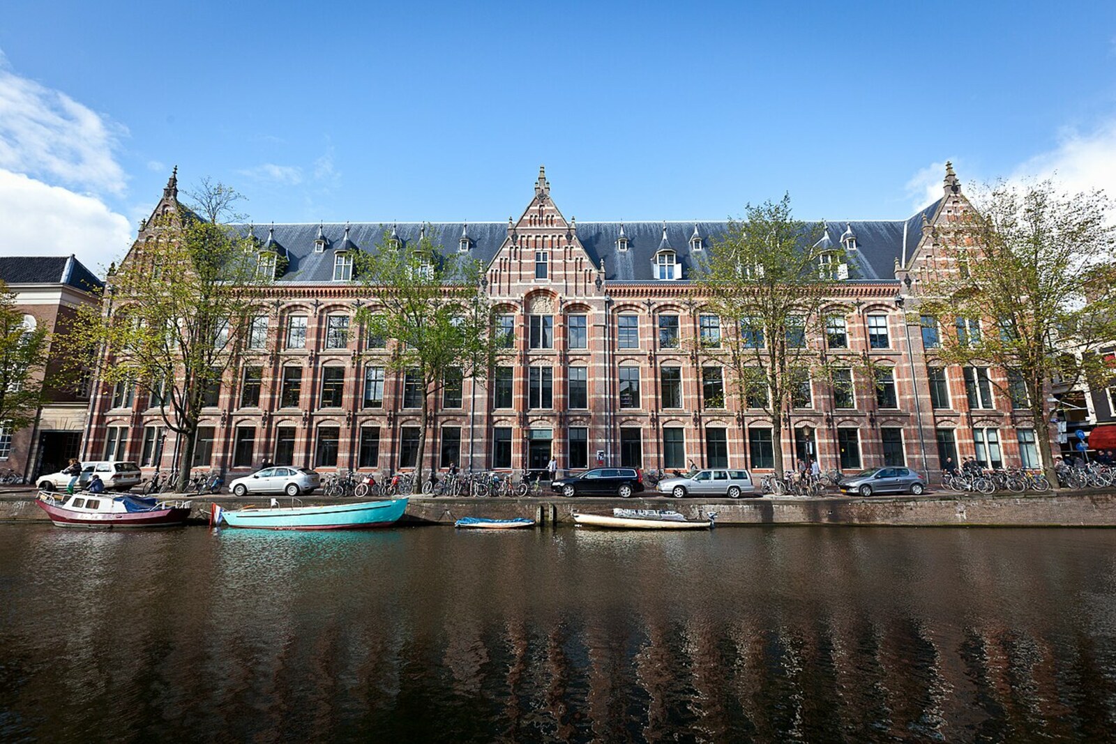 A red-brick building with classical windows and coats of arms on its facade.