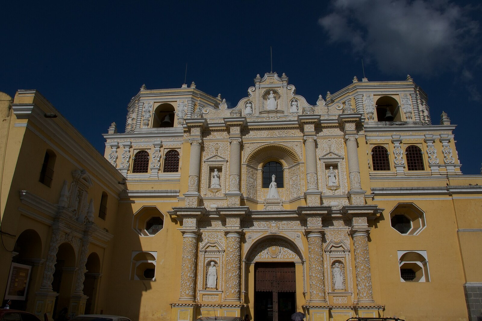 Yellow façade of La Merced Church with white stucco decoration and two low towers