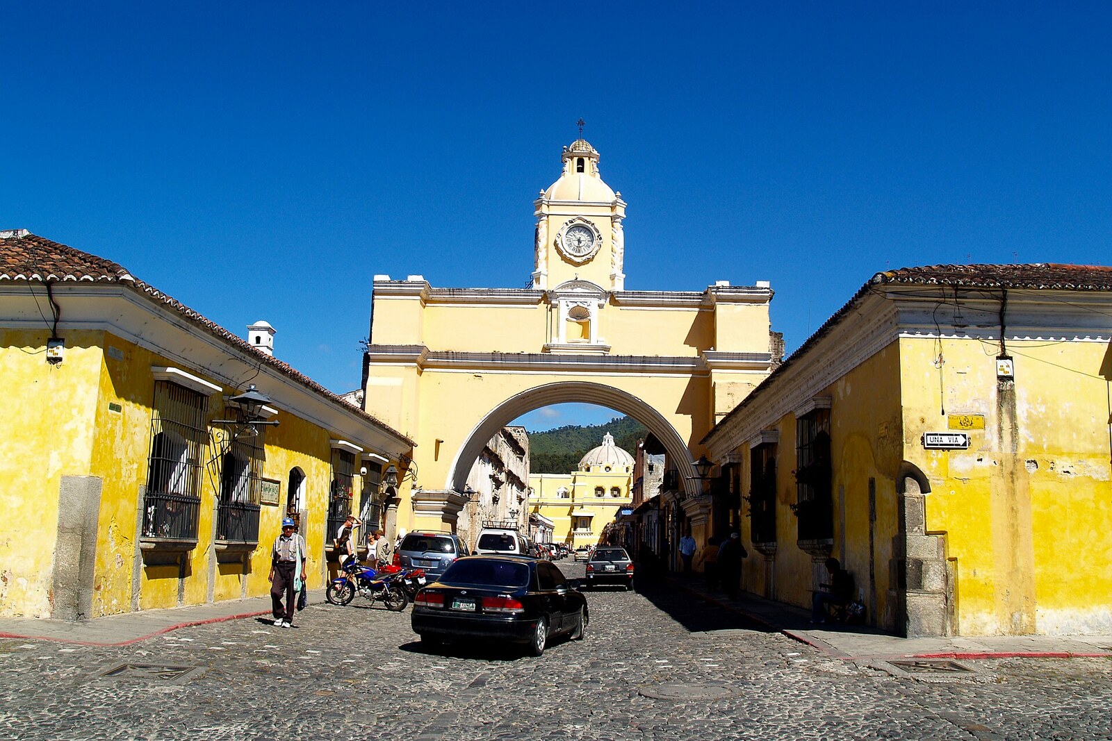 Yellow Santa Catalina Arch with a small clock tower above a cobbled street