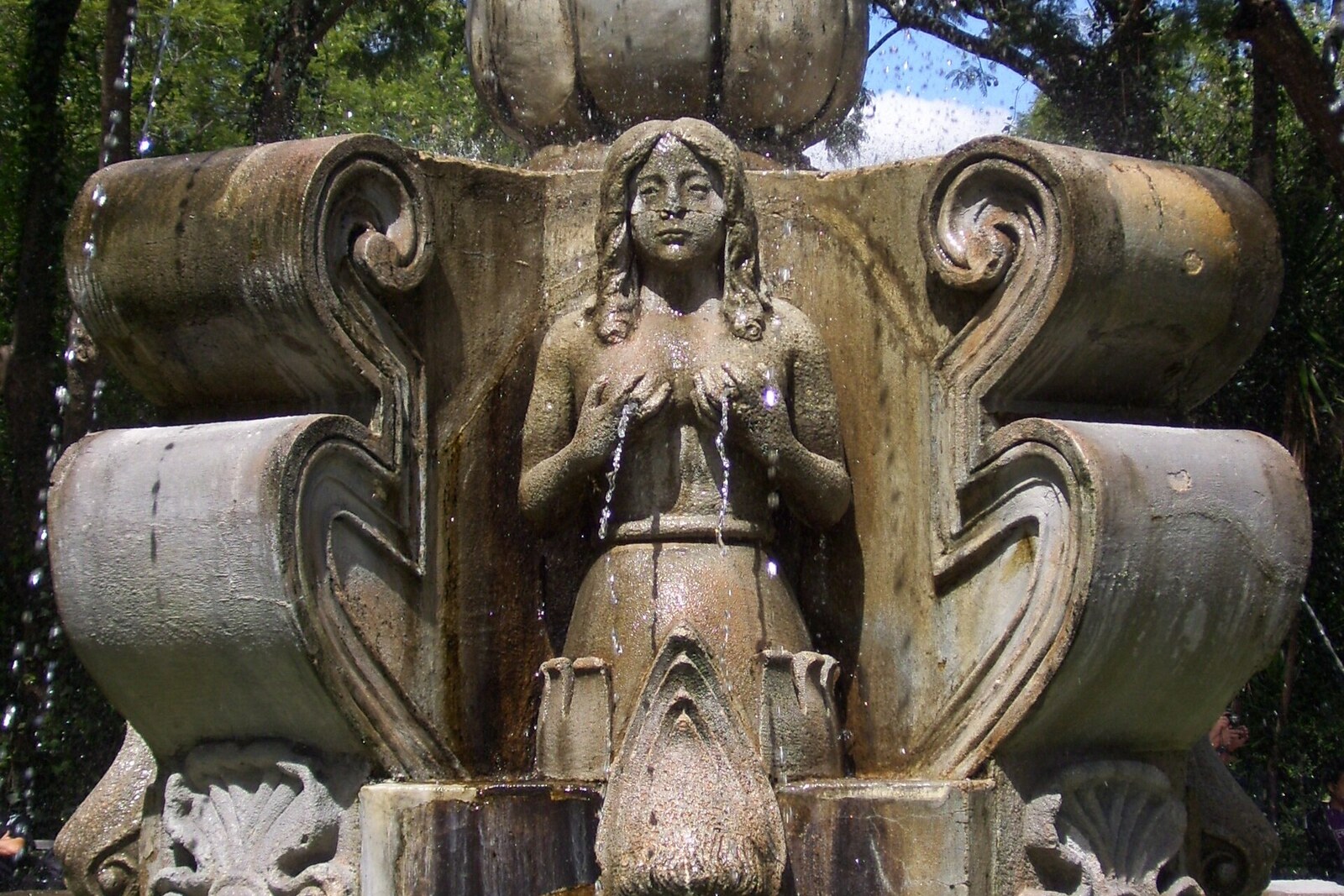 A stone figure of a siren with streams of water in the Central Park fountain
