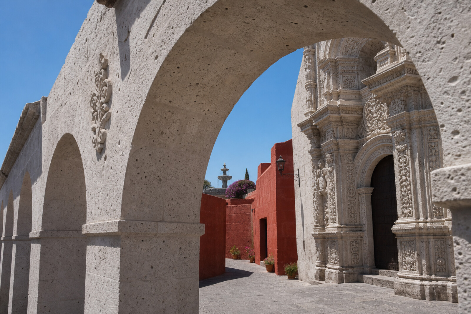 A white arcade and carved portal give way to a red street at Monastery of Santa Catalina de Siena.
