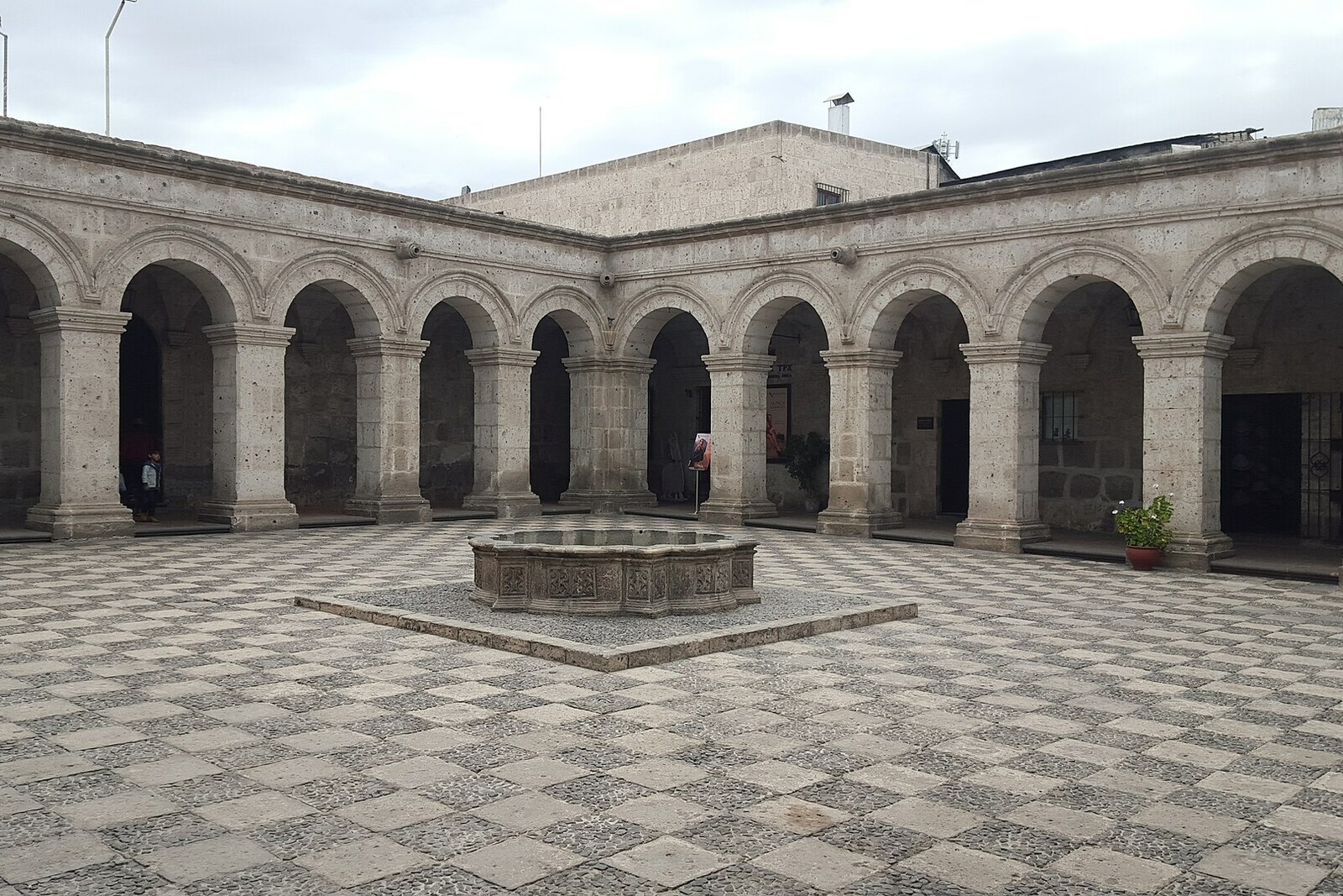 A white arcade and a stone courtyard of the Cloisters of the Society of Jesus.