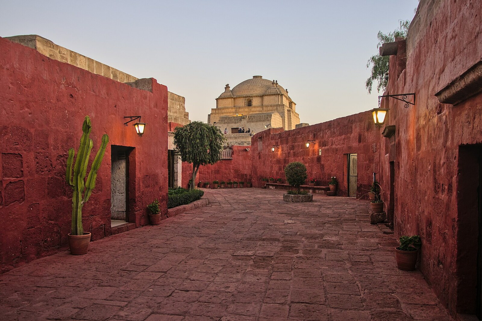 A red street inside the Monastery of Santa Catalina de Siena, with a dome in the distance.