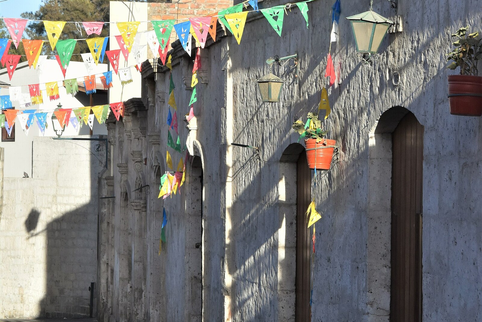 A narrow lane in San Lázaro with stone facades and small flags.