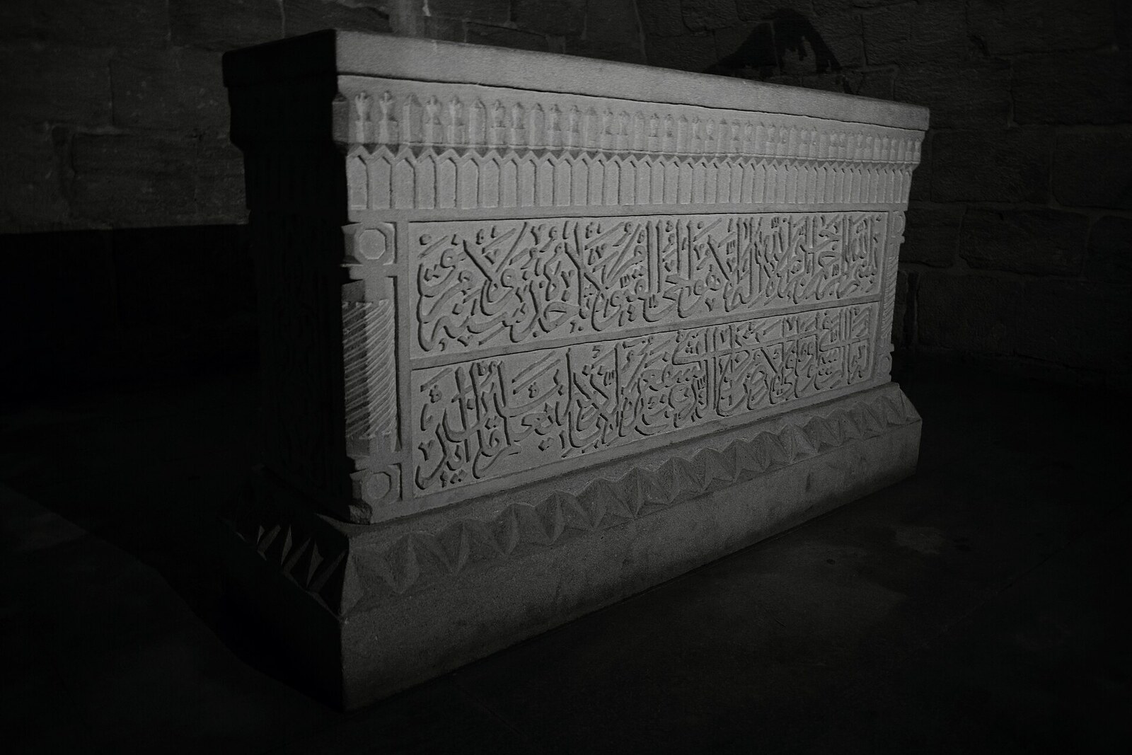 A carved stone sarcophagus in the dark mausoleum of Bakuvi.