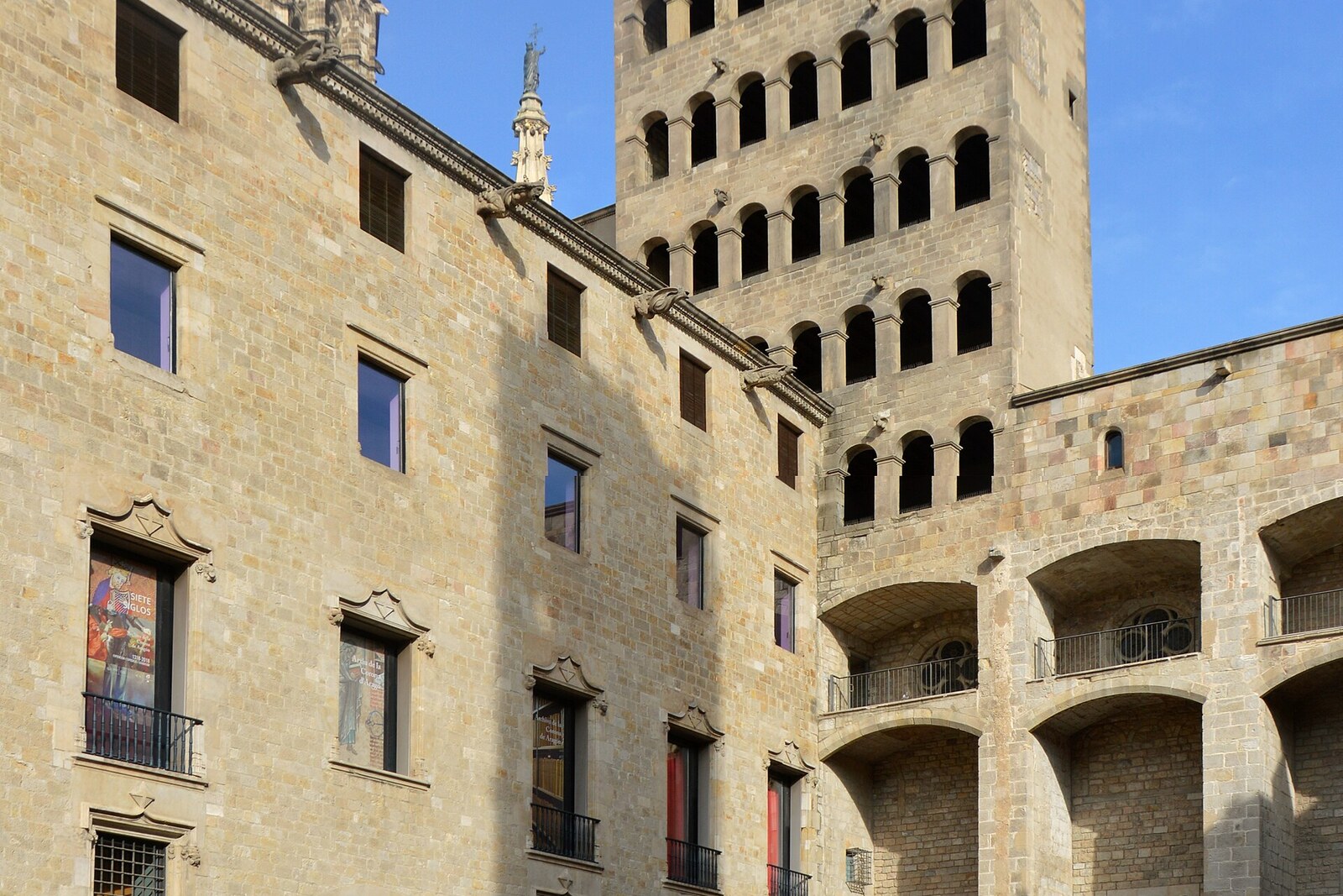 A stone square with ancient buildings and a tower in Barcelona in the morning