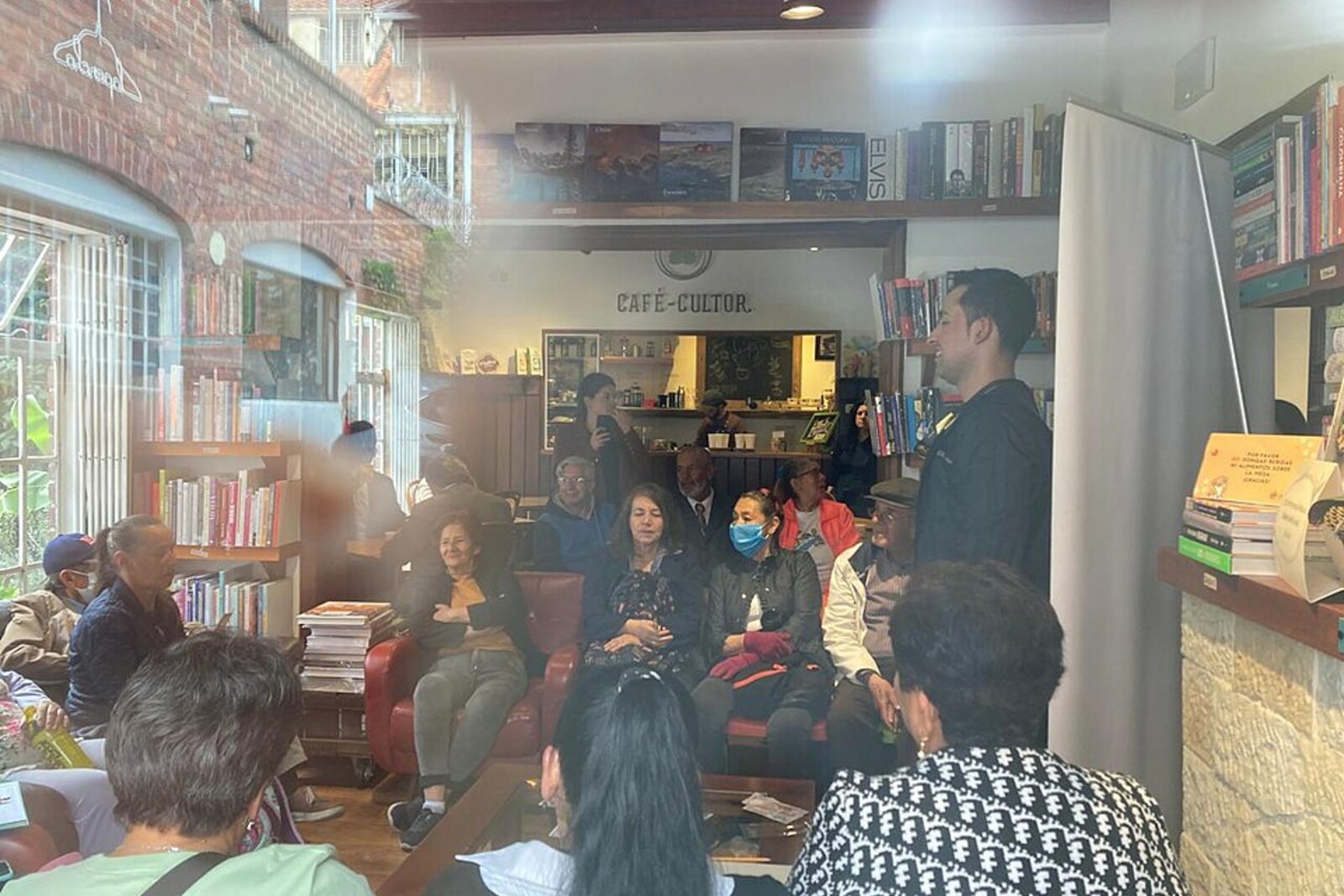 Interior of Wilborada 1047 during a joint cultural gathering: bookshelves, Café Cultor, and visitors.