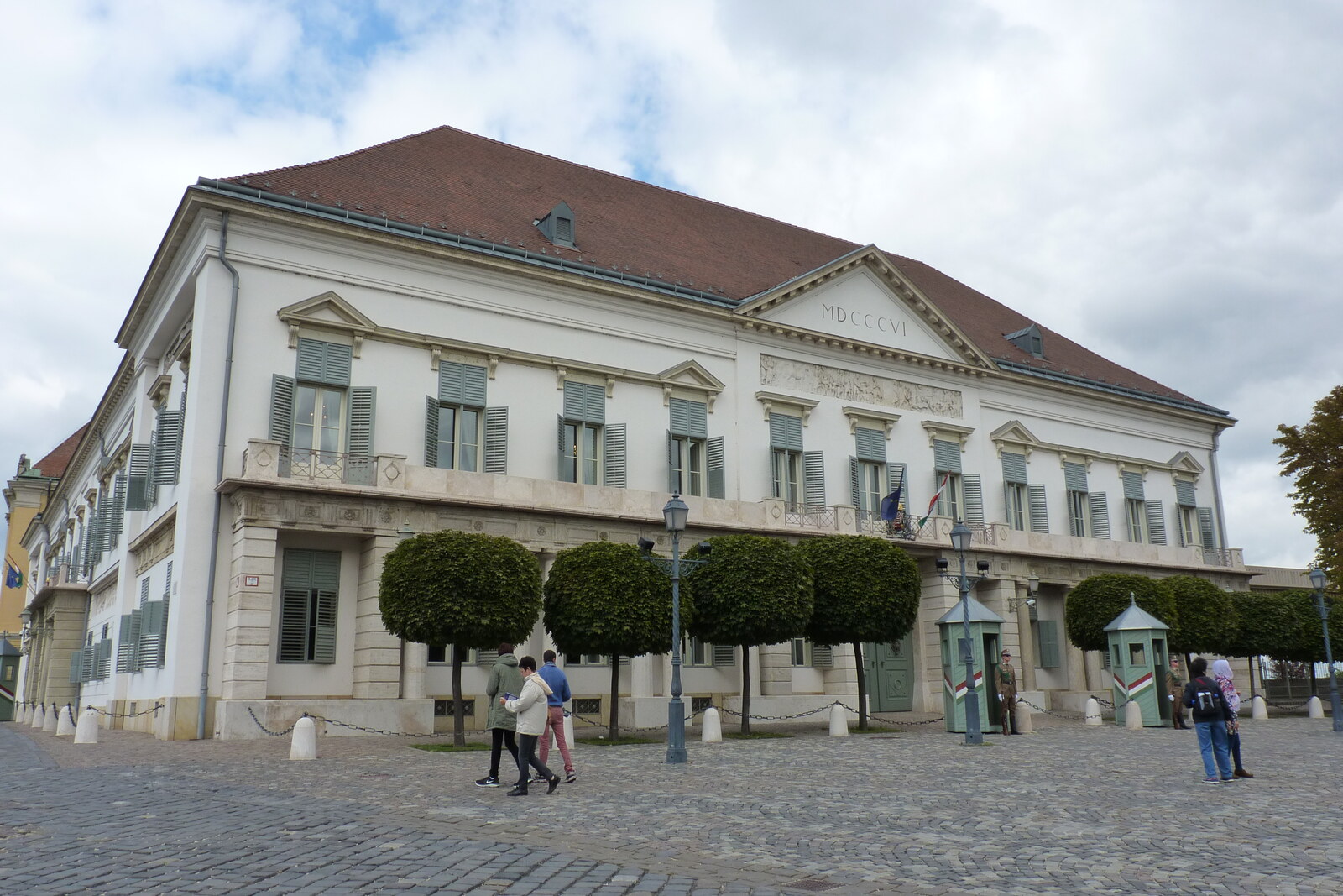 The light-colored façade of Sándor Palace on a paved square.