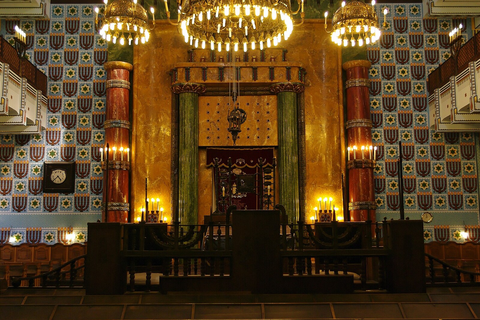 The interior of an Orthodox synagogue with a women's gallery and ornamentation.