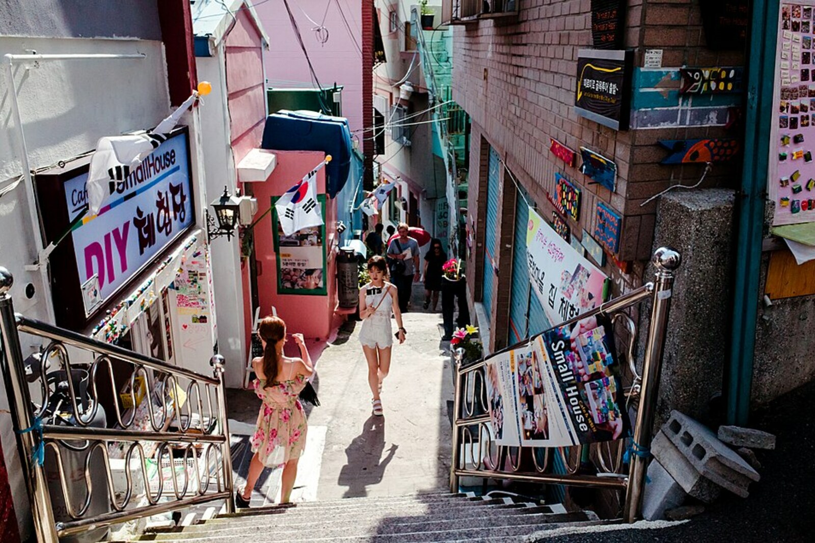A narrow alley in Gamcheon with workshop signs and small houses.