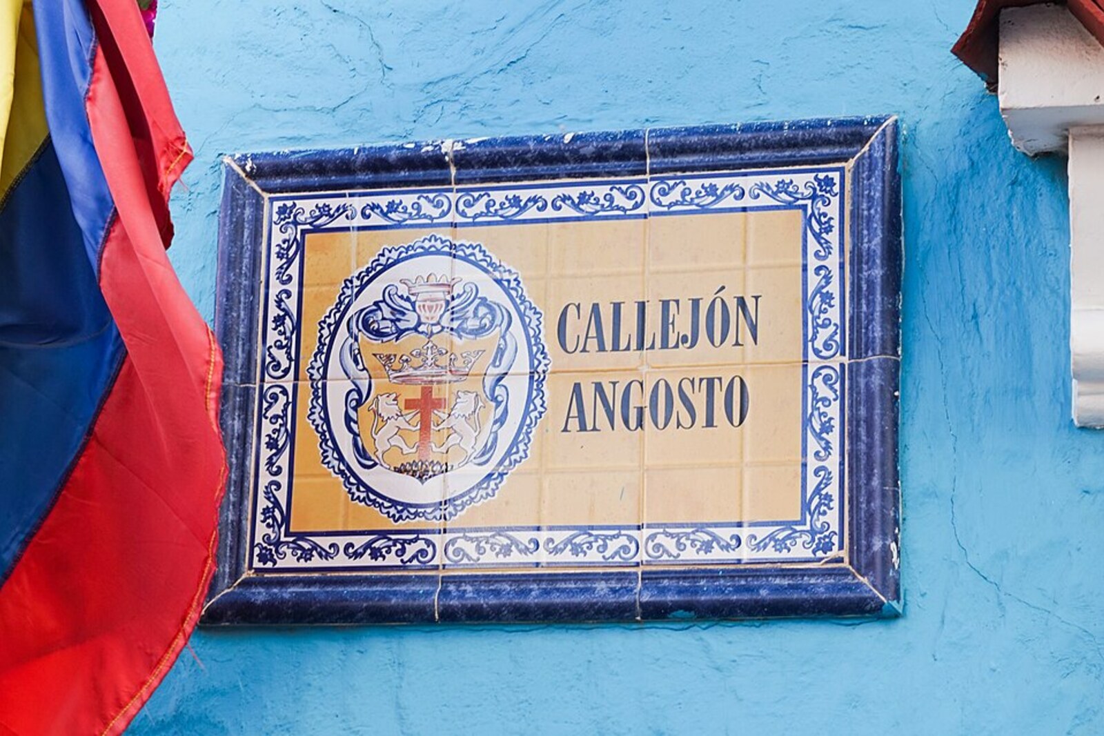 The narrow Callejón Angosto in Getsemaní, with colorful umbrellas above low façades.