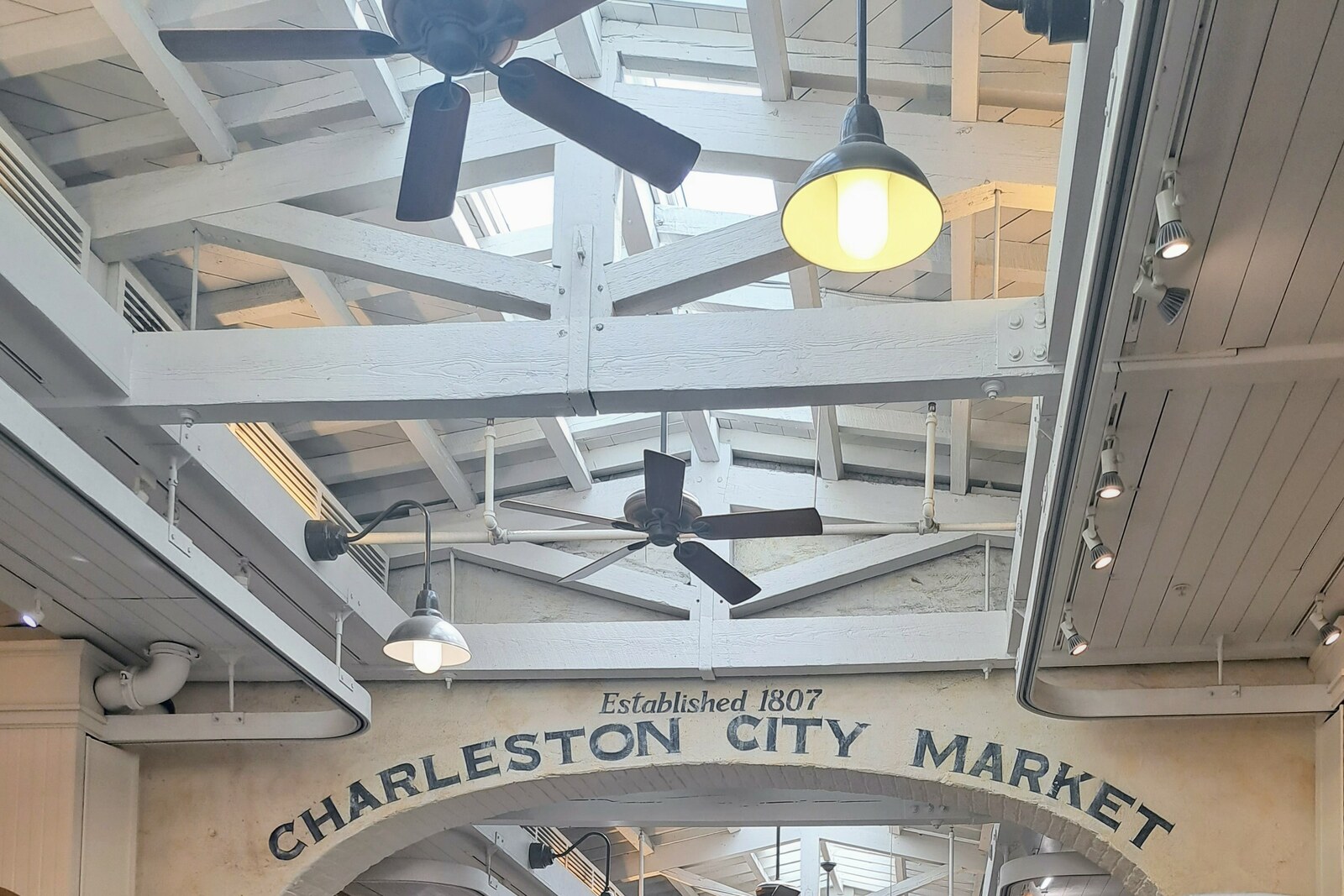 Interior of the Charleston City Market with arches, beams, and rows of stalls.