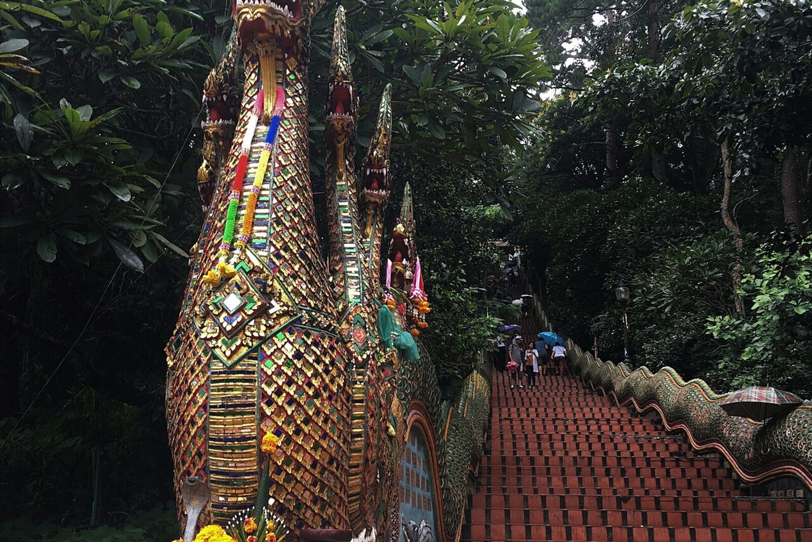 The Naga Stairway leads to Wat Phra That Doi Suthep, decorated with mosaic serpents and surrounded by forest