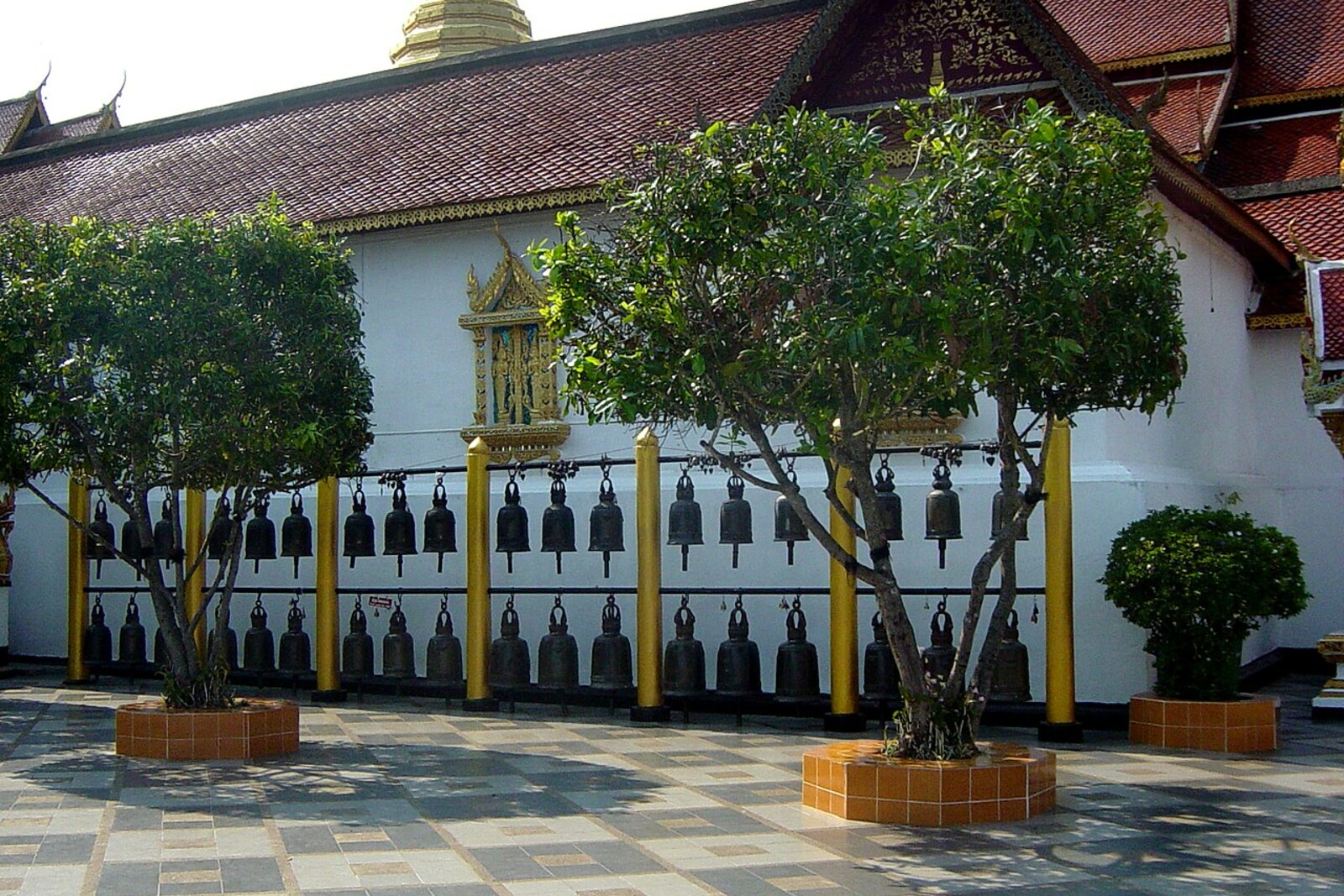 A row of large bells under a canopy on the grounds of Wat Phra That Doi Suthep