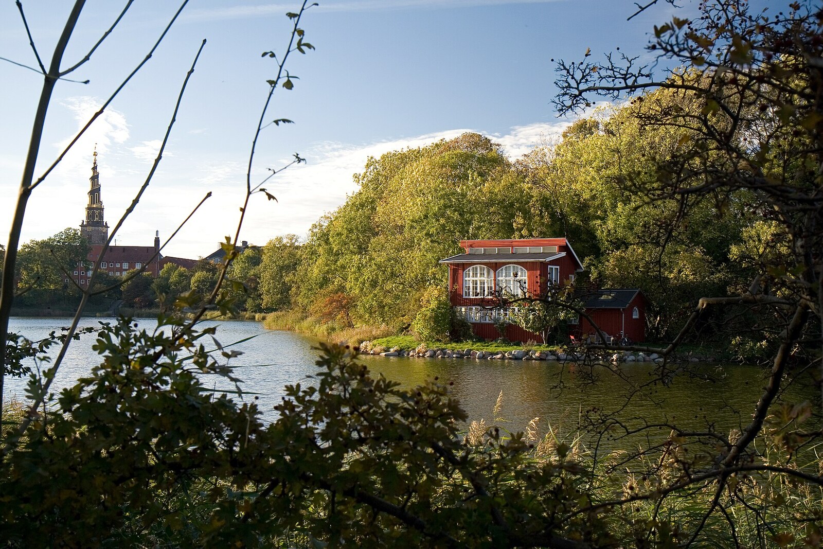 A small house on the bank of the Stadsgraven moat and the spire of the Church of Our Saviour on the horizon.