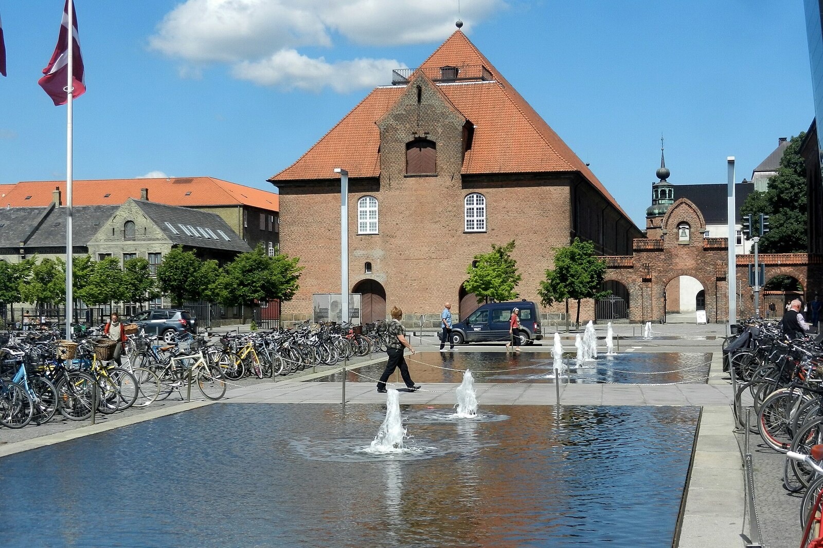 A spacious paved square with trees and steps down to the canal near the black library