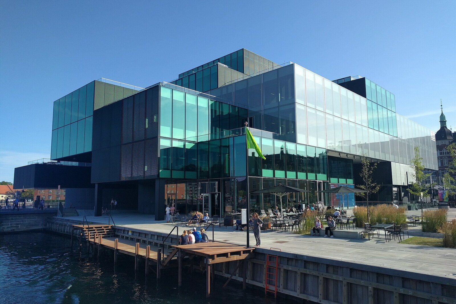 Modern green glass cube of BLOX on the waterfront, with windows reflecting the water