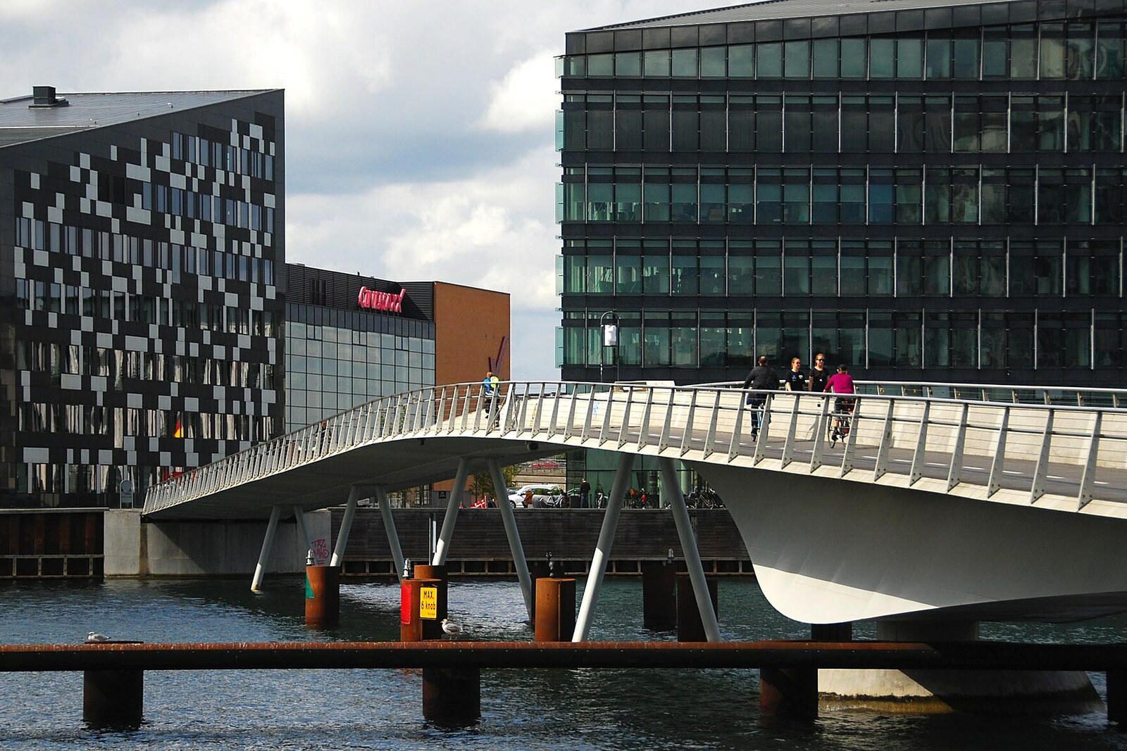 The gray Bryggebroen pedestrian-and-cyclist crossing with love locks and a city backdrop