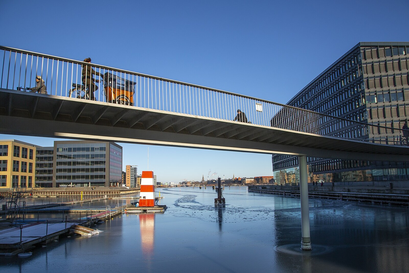 The bright-orange winding Cykelslangen bike path, overhanging the water amid modern buildings