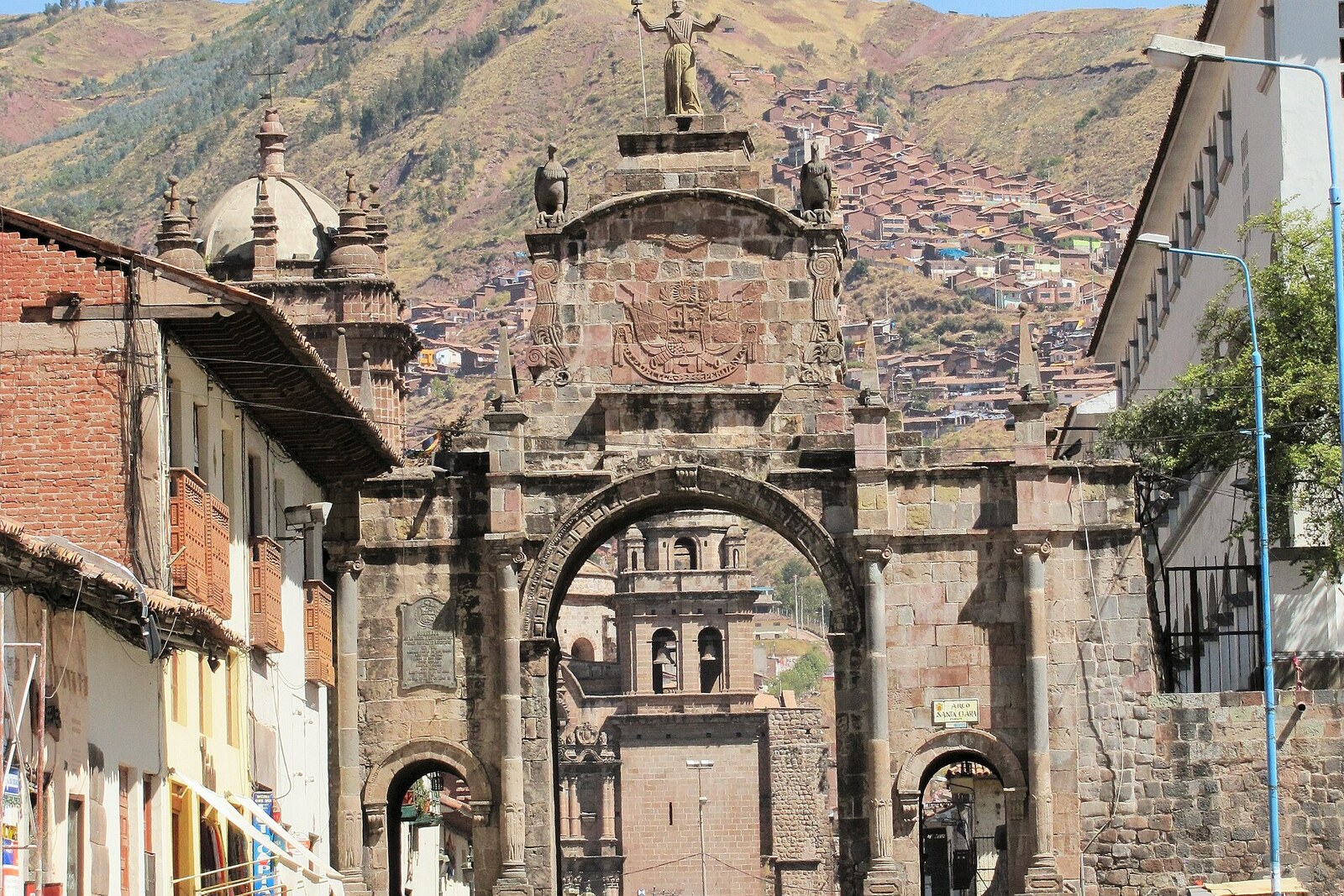 Arco de Santa Clara in Cusco, with three openings and a statue on top.
