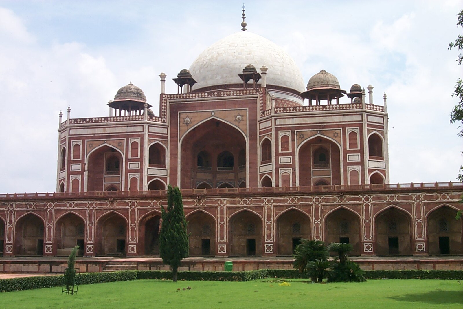 Humayun's Tomb, a red sandstone mausoleum with a white dome, surrounded by greenery.