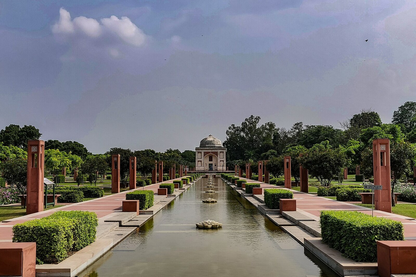 The old octagonal mausoleum of Sunderwala Burj on a green lawn in the park.