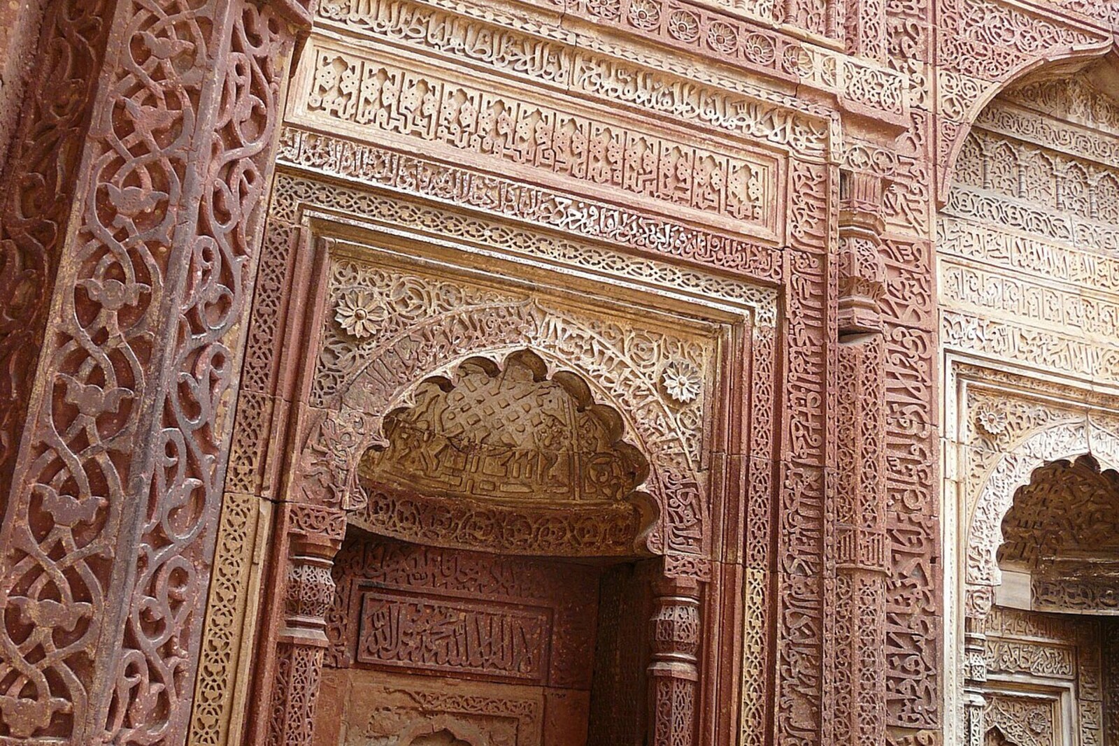 A carved mihrab with ornament and Arabic inscriptions inside the Tomb of Iltutmish.