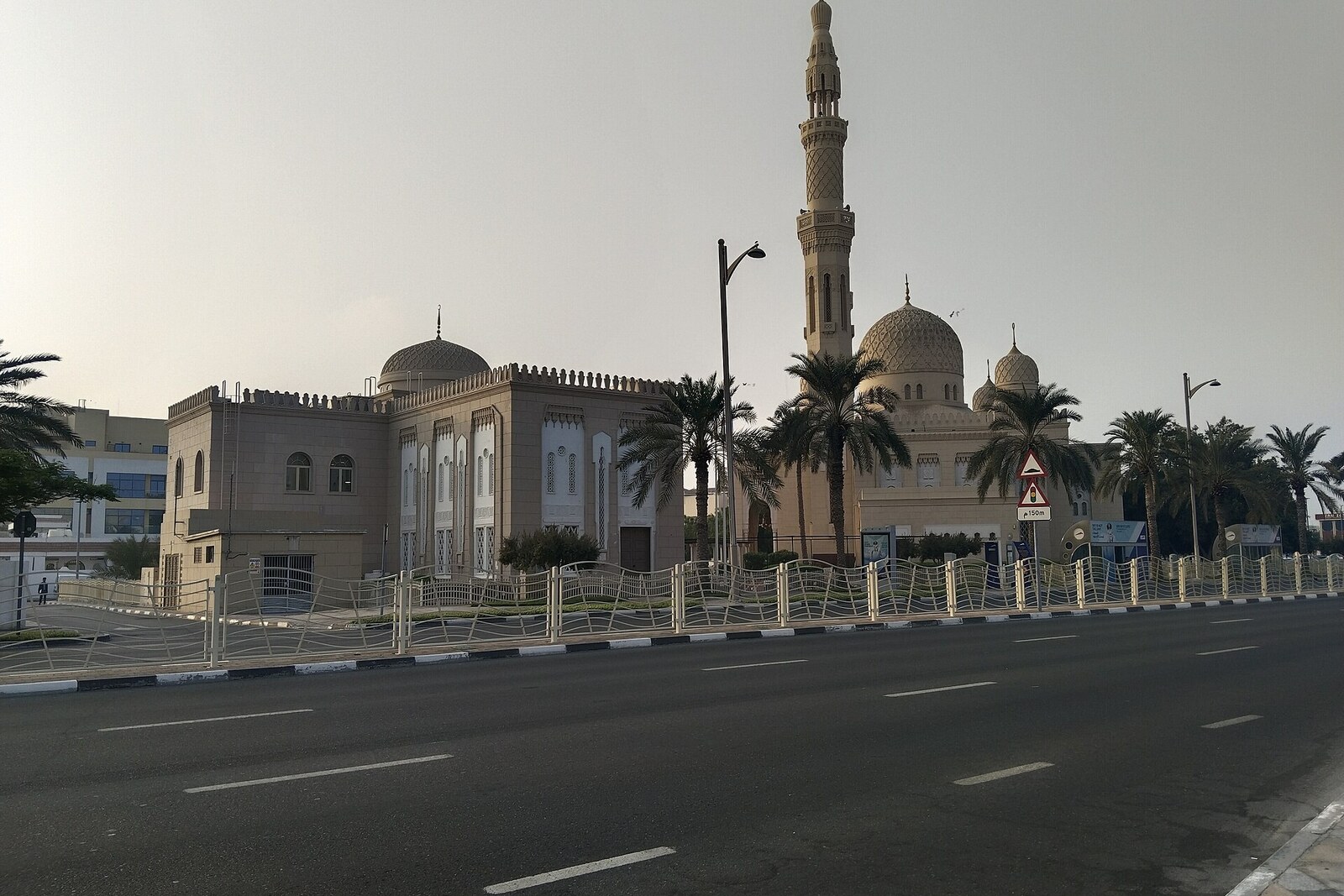 White mosque with domes and minarets against a blue sky and palm trees