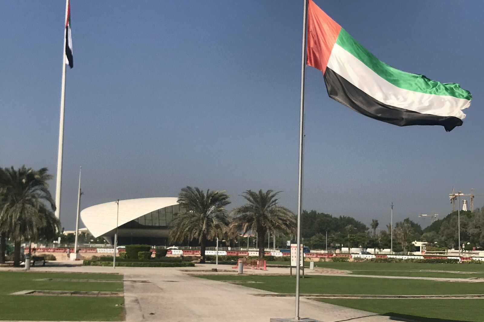 A white modern museum with the United Arab Emirates flag in the foreground