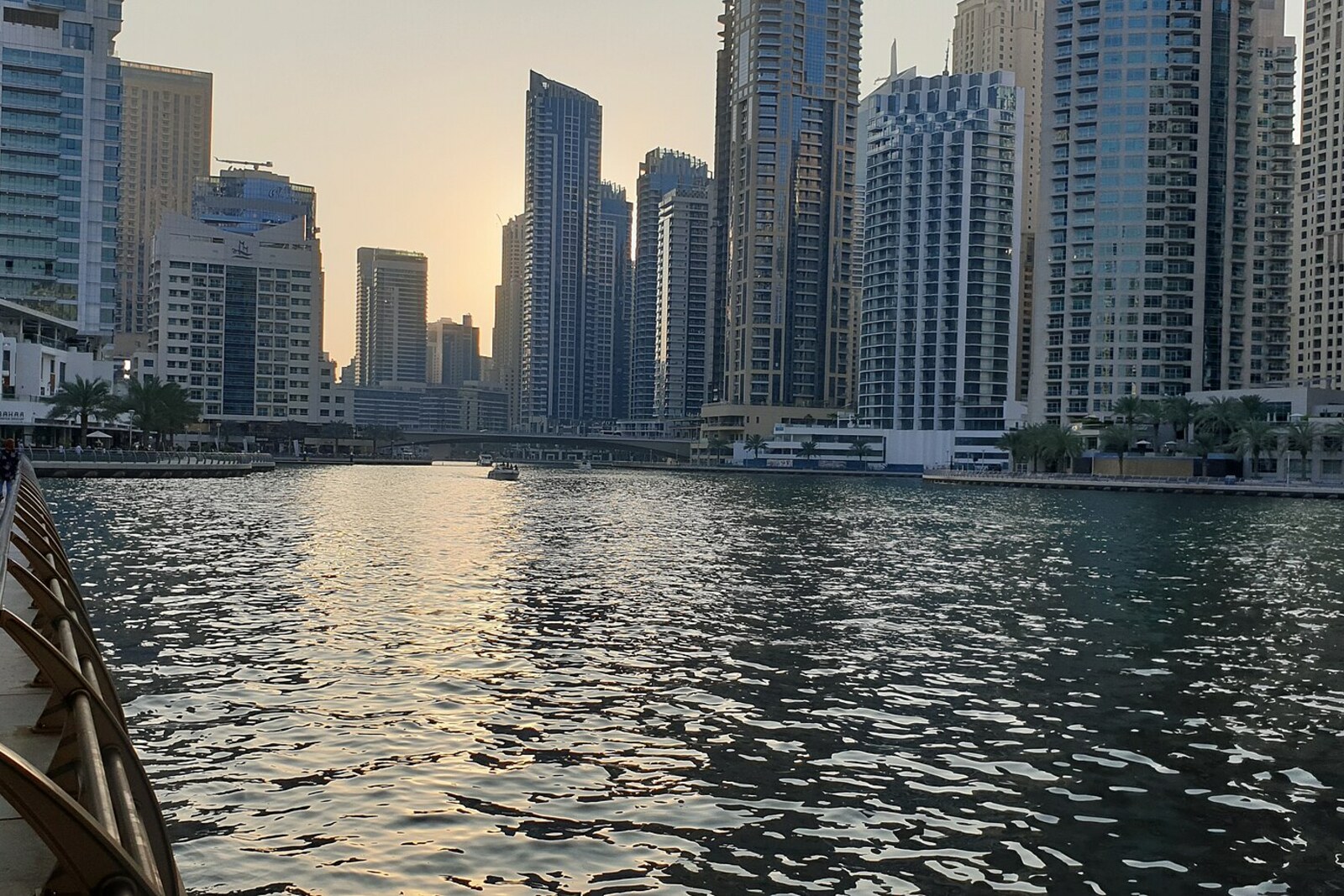 Wide view of the canal and Dubai Marina buildings by Dubai Marina Mall, with white yachts moored along the waterfront.
