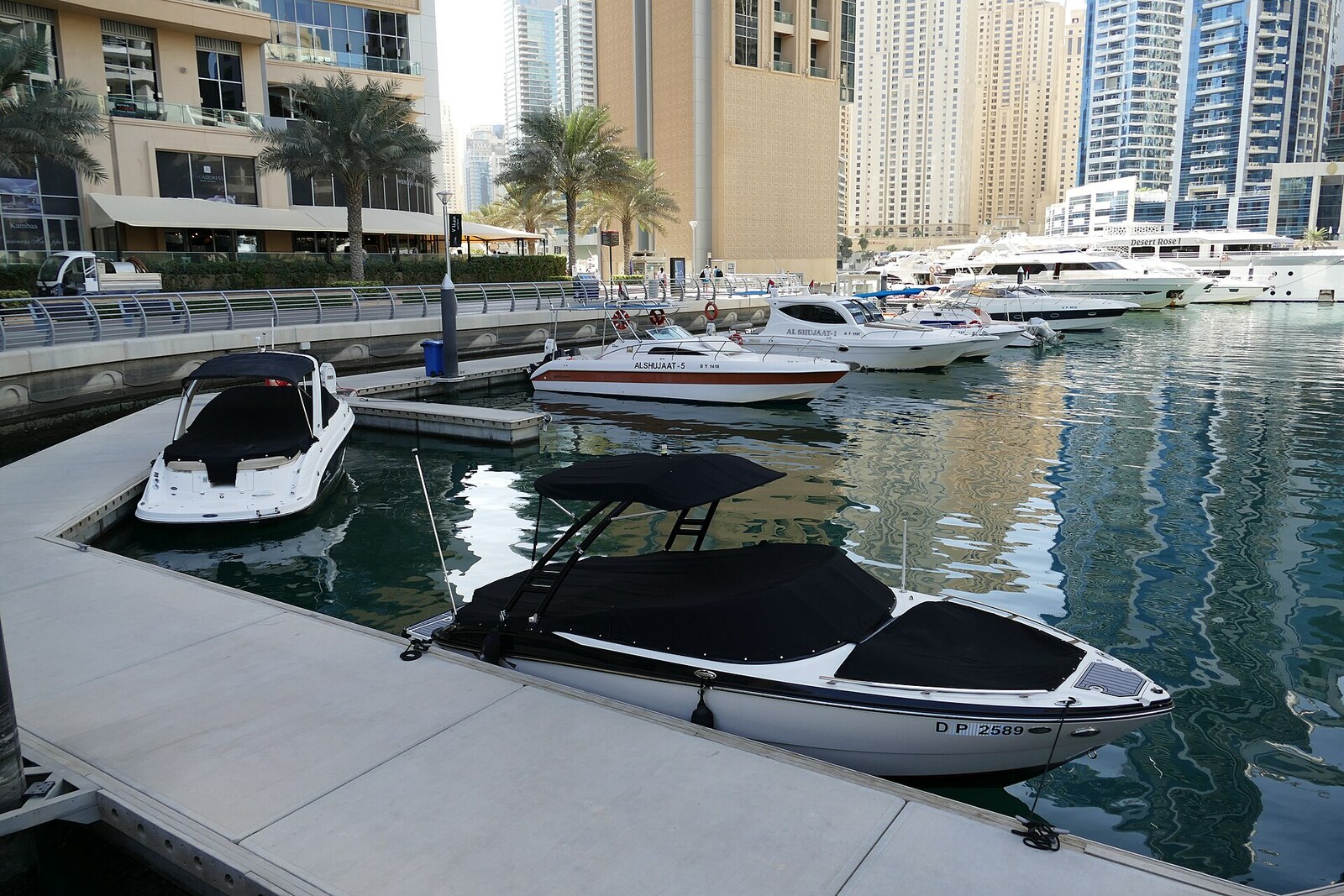 Der runde gläserne Turm Pier 7 am Ufer von Dubai Marina, im Wasser gespiegelt.