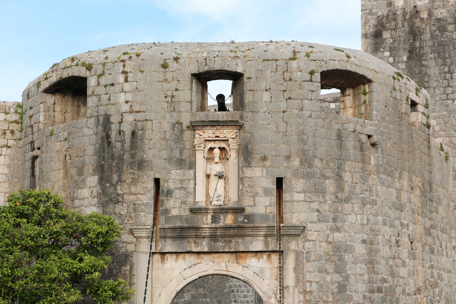 La Puerta de Pile, con arco de piedra, estatua de San Blas y la muralla de Dubrovnik.