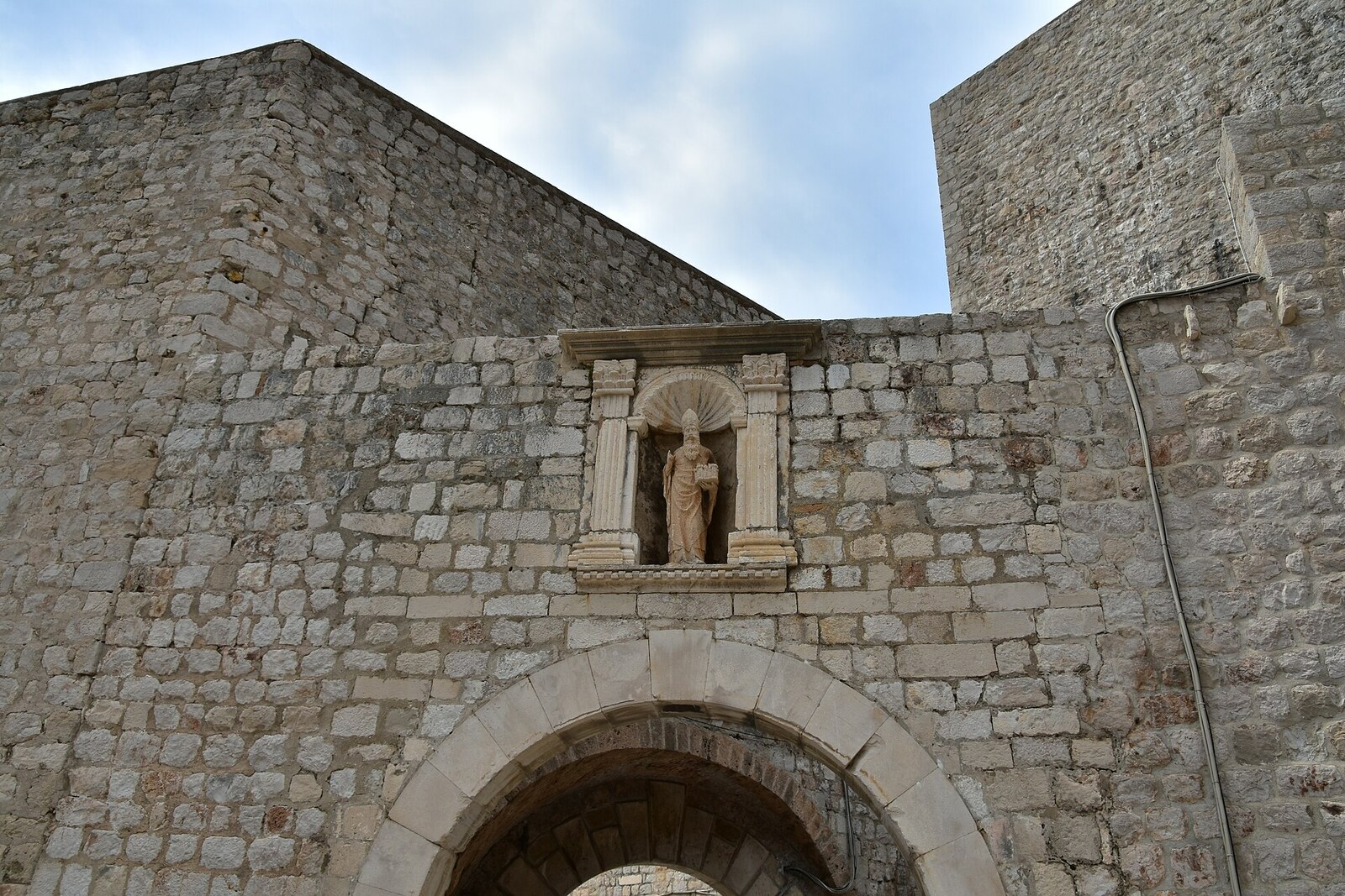 Ploče Gate — a stone entrance with an arch and a statue above a deep moat.