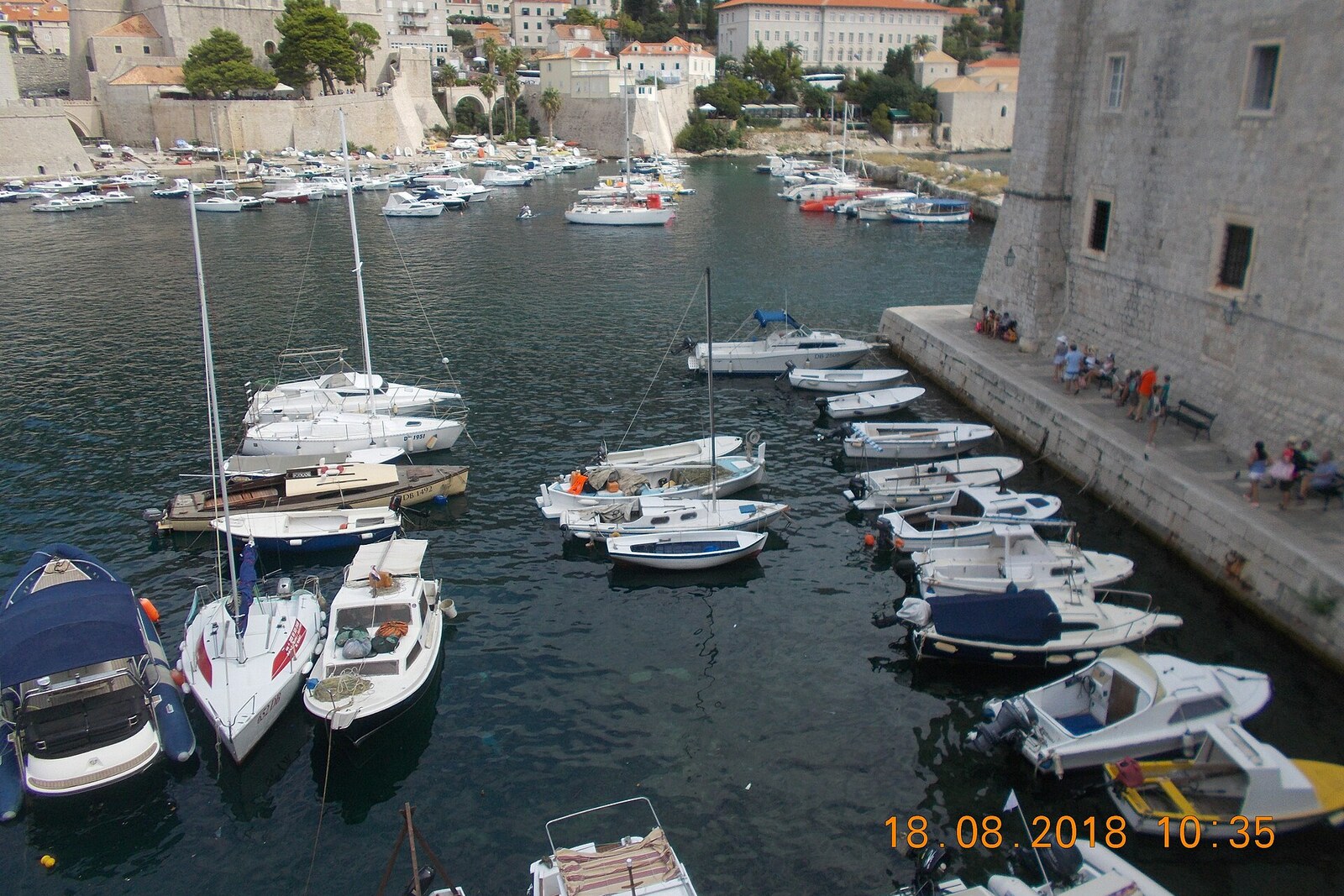 Boats on the water in Dubrovnik's Old Harbour, with the city walls in the background.
