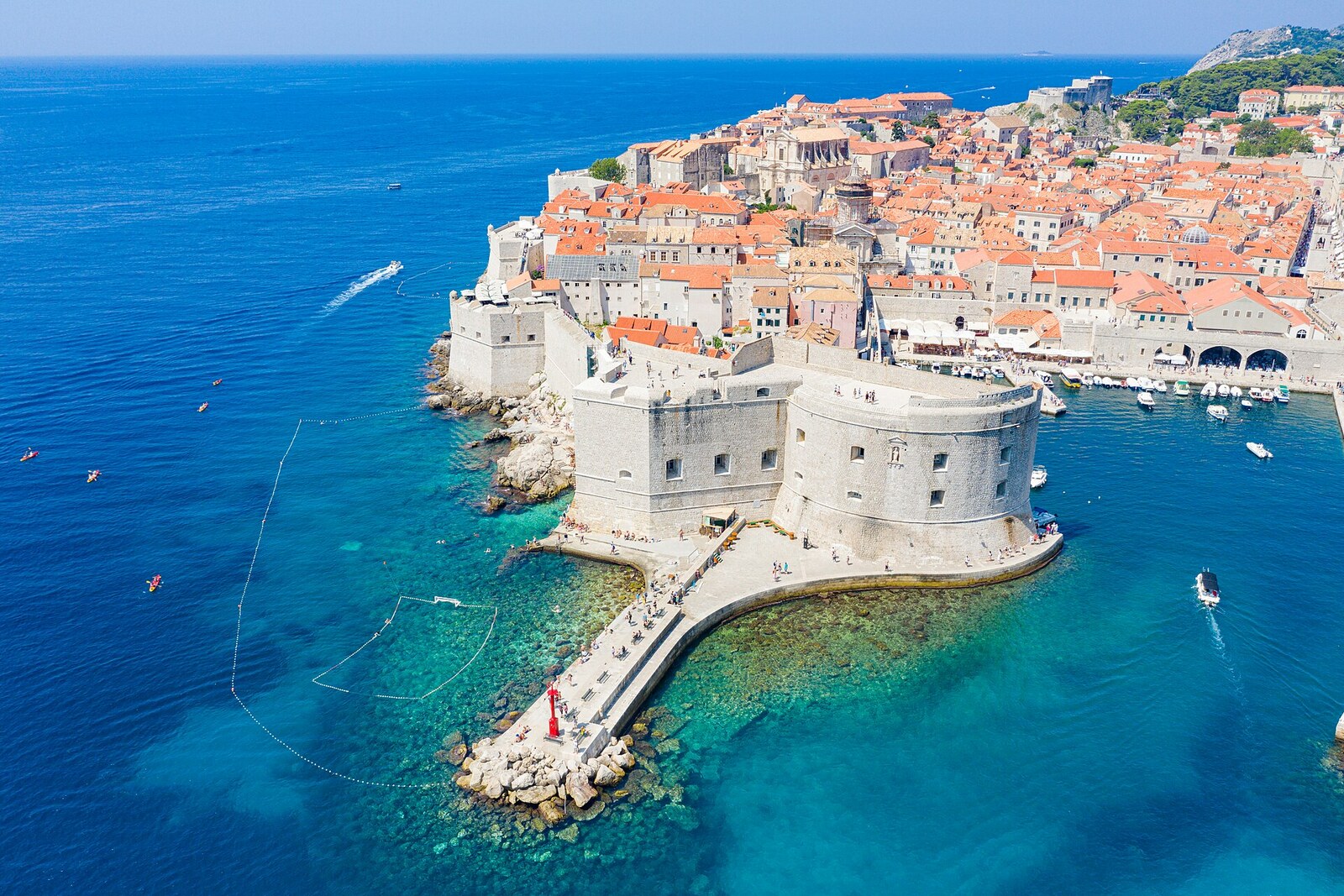 La jetée de pierre de Porporela, avec des personnes et une vue sur les remparts de Dubrovnik.