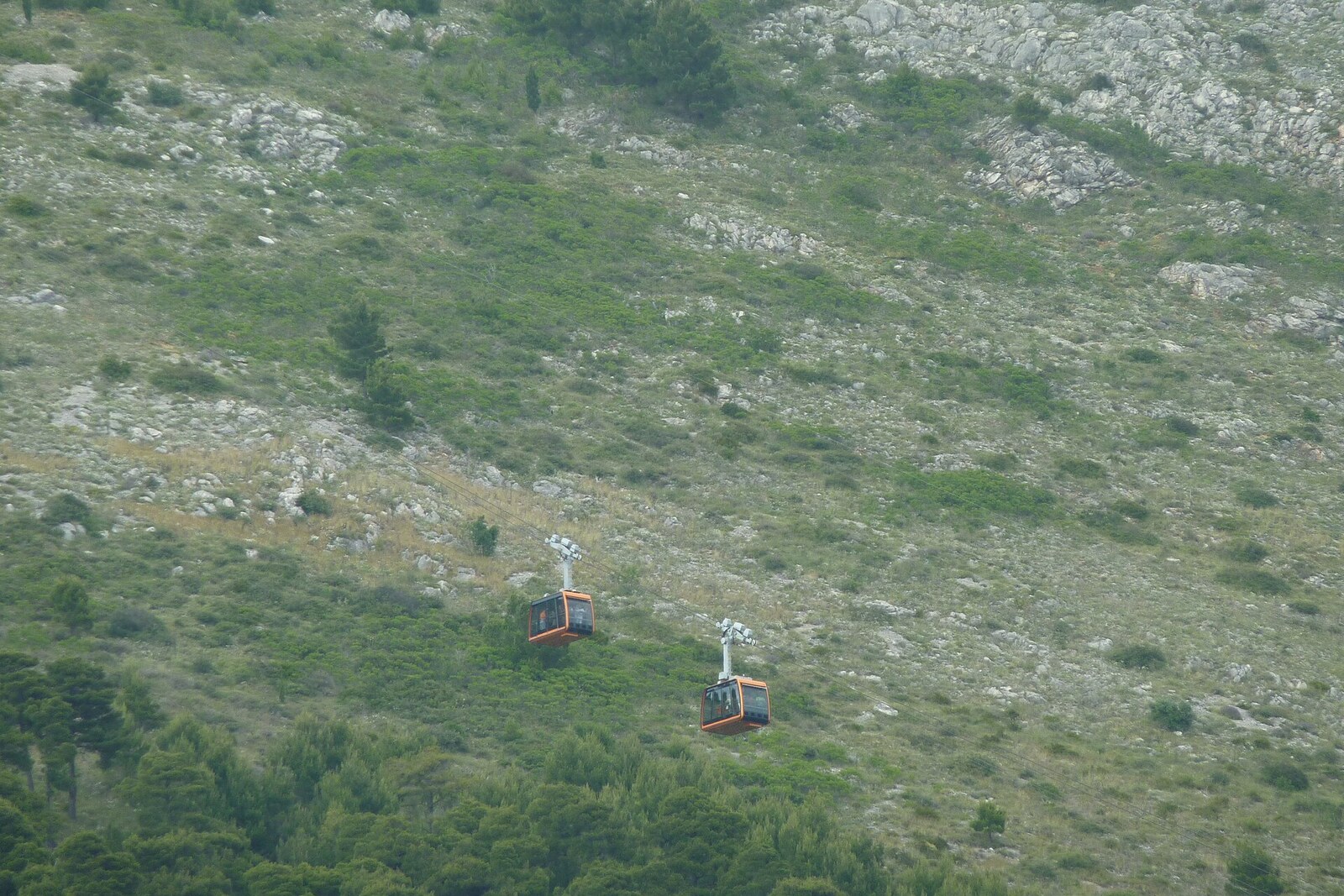 A cabin of the Dubrovnik Cable Car approaches the upper station against a backdrop of blue sea