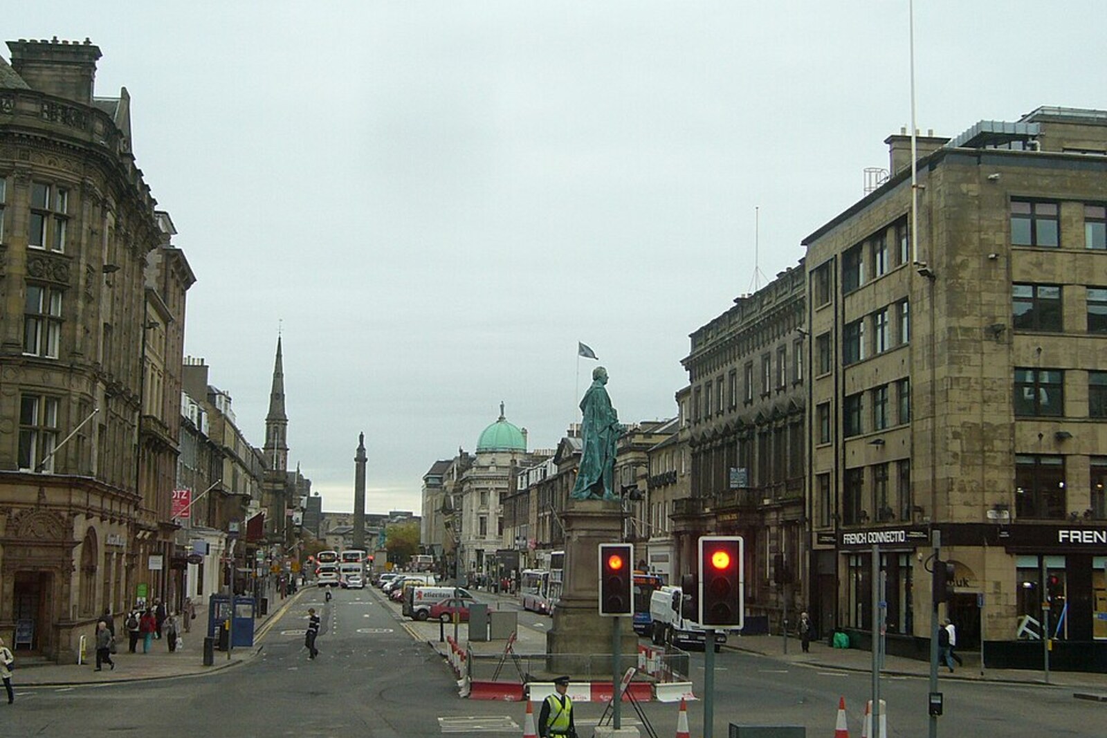 View along George Street toward a monument and rows of Georgian buildings beneath a blue sky.