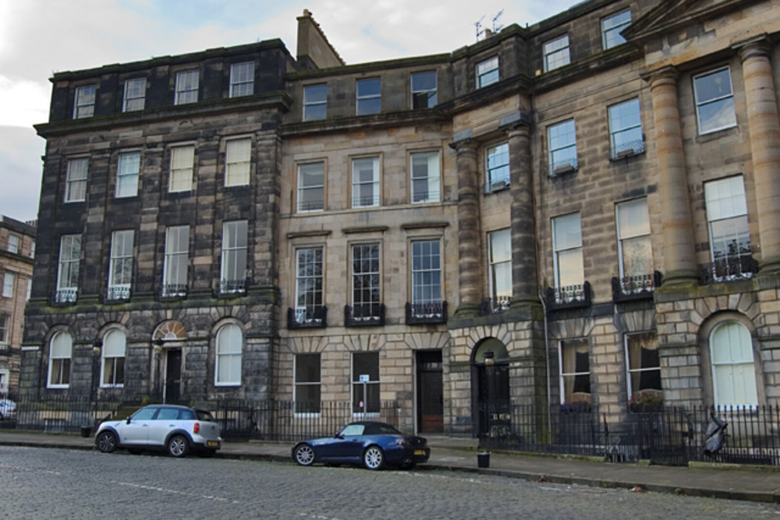 A row of semicircular Georgian houses on Moray Place with parking in front of them.