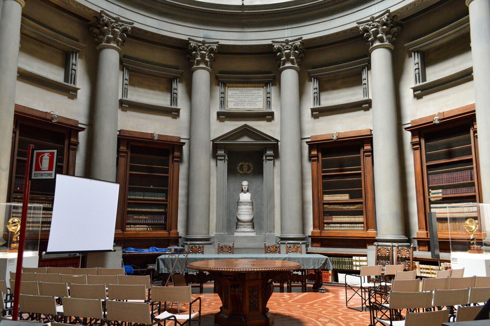 The stone hall of the Medici Laurentian Library, with large windows and wooden benches.