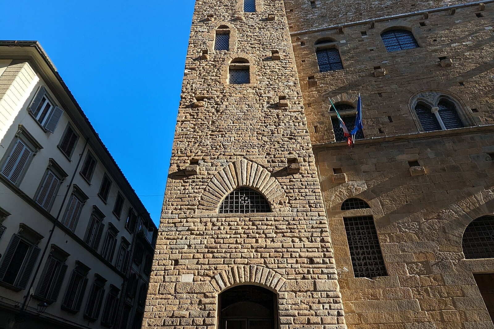 View of the stone tower and facade of the Bargello museum with crenellated crowns.