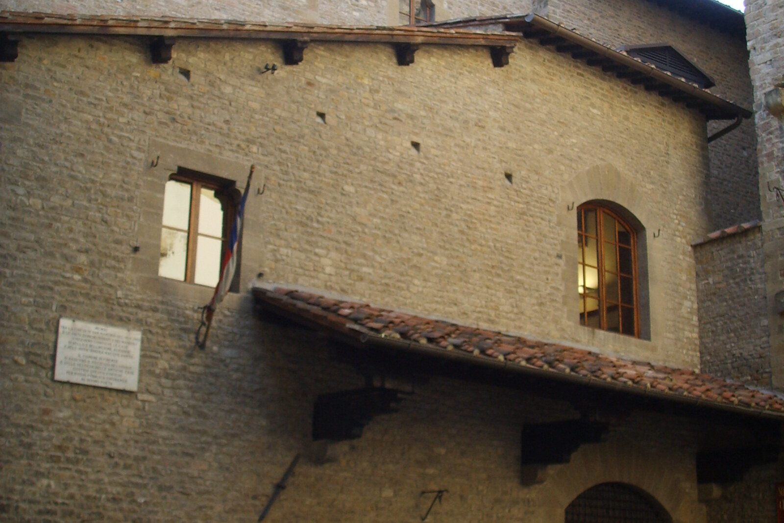 A narrow stone house with flags and a coat of arms—the façade of Dante's House Museum in Florence.
