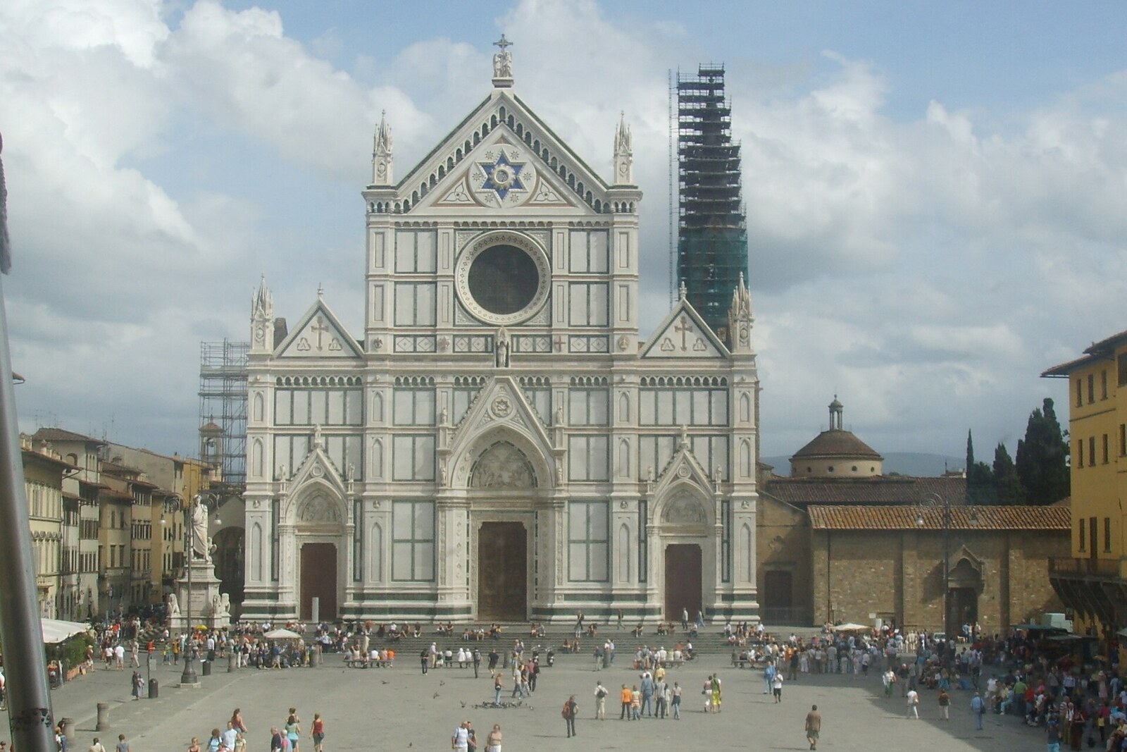 Panoramic view of the large stone Piazza Santa Croce, with the basilica's Neo-Gothic façade and the Dante monument.