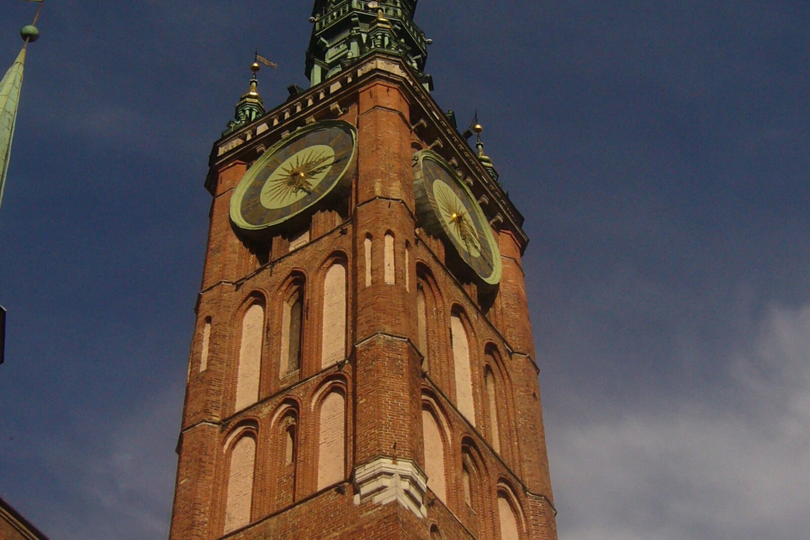 The brick tower of Gdańsk's Main Town Hall, with a clock and a tall spire.