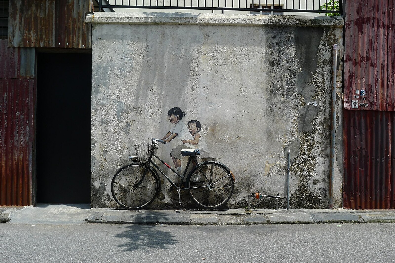 Children on a Bicycle mural on Armenian Street, showing two children riding a real bicycle attached to a wall.
