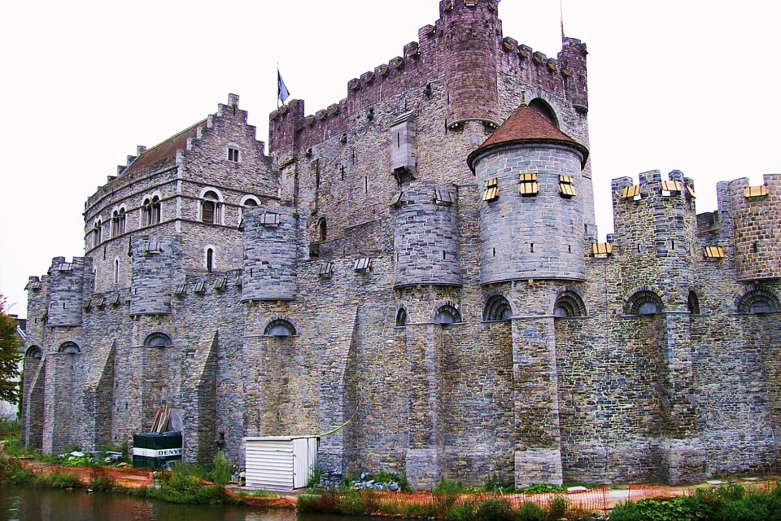 The gray stone Gravensteen castle above a moat, reflected in the water