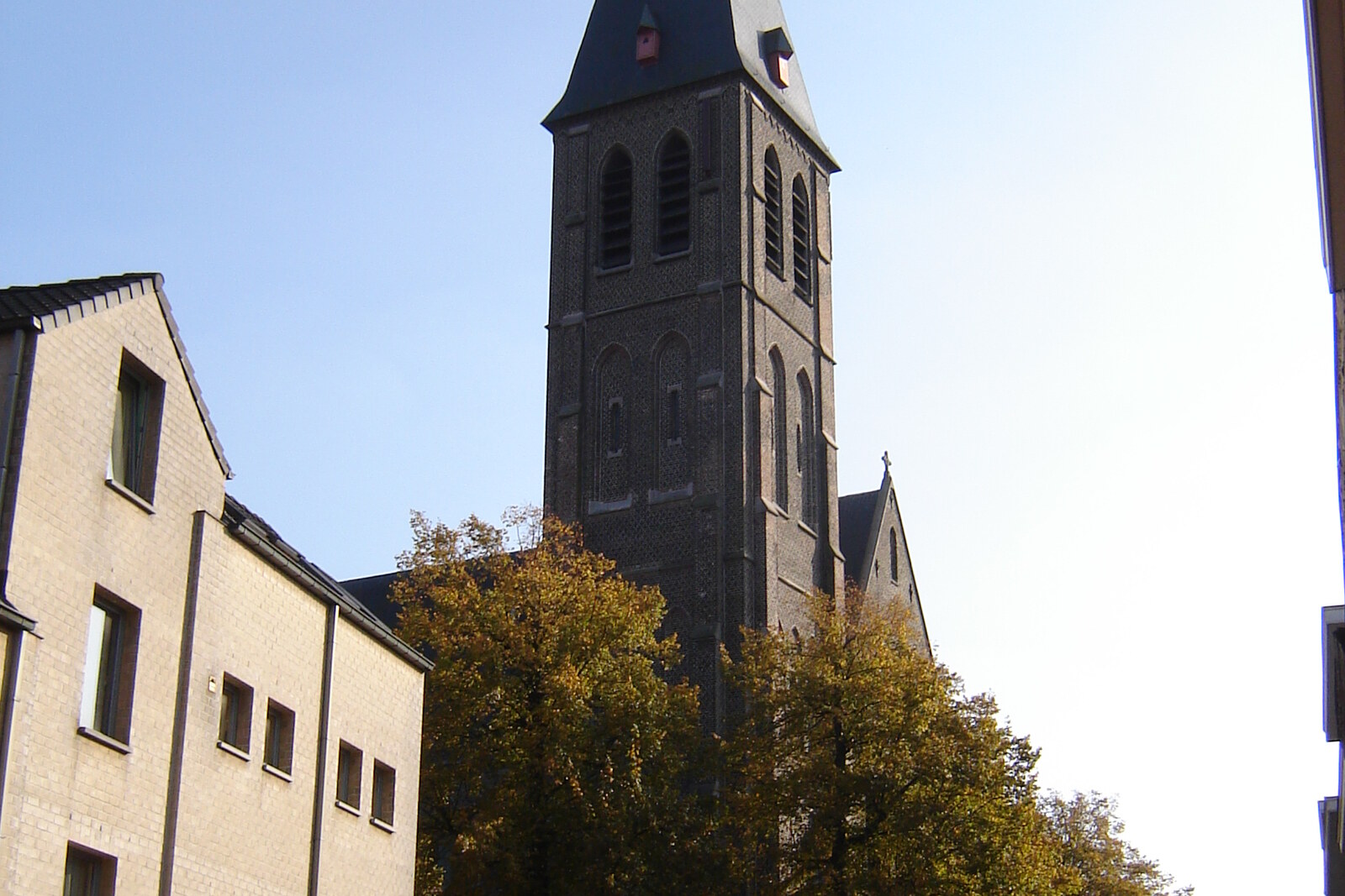 Facade of the neo-Gothic Saint Macharius Church, with a tower and arches of red brick and blue stone.